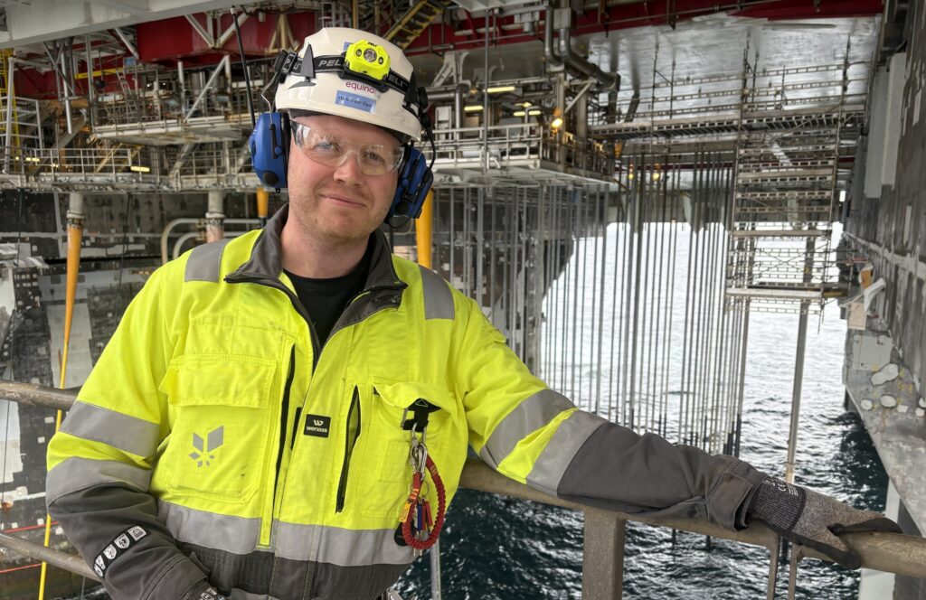 Man in a reflective jacket with safety glasses, helmet and hearing protection.